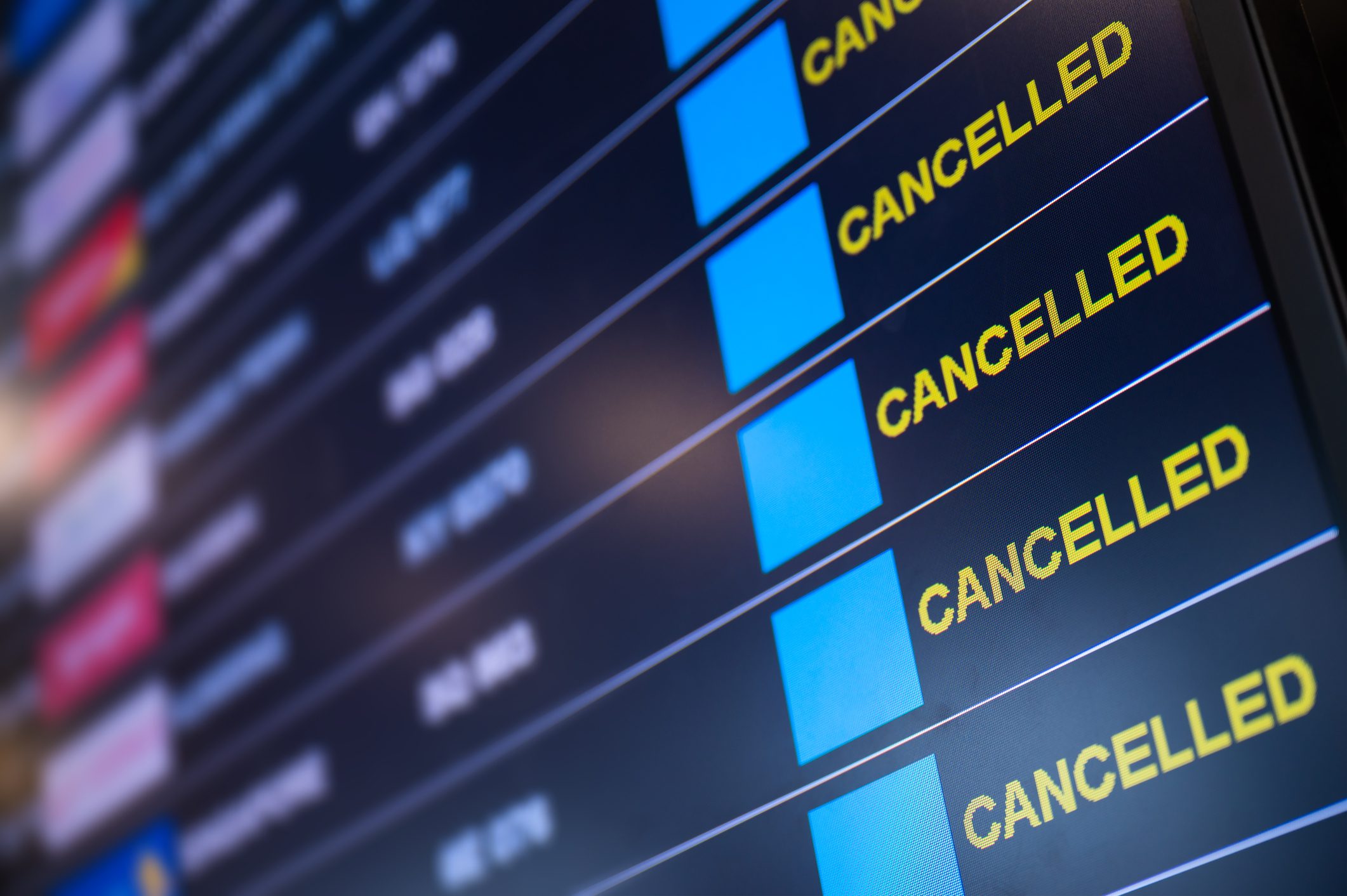 An up-close photo of the departure board at an airport showing a list of cancelled flights